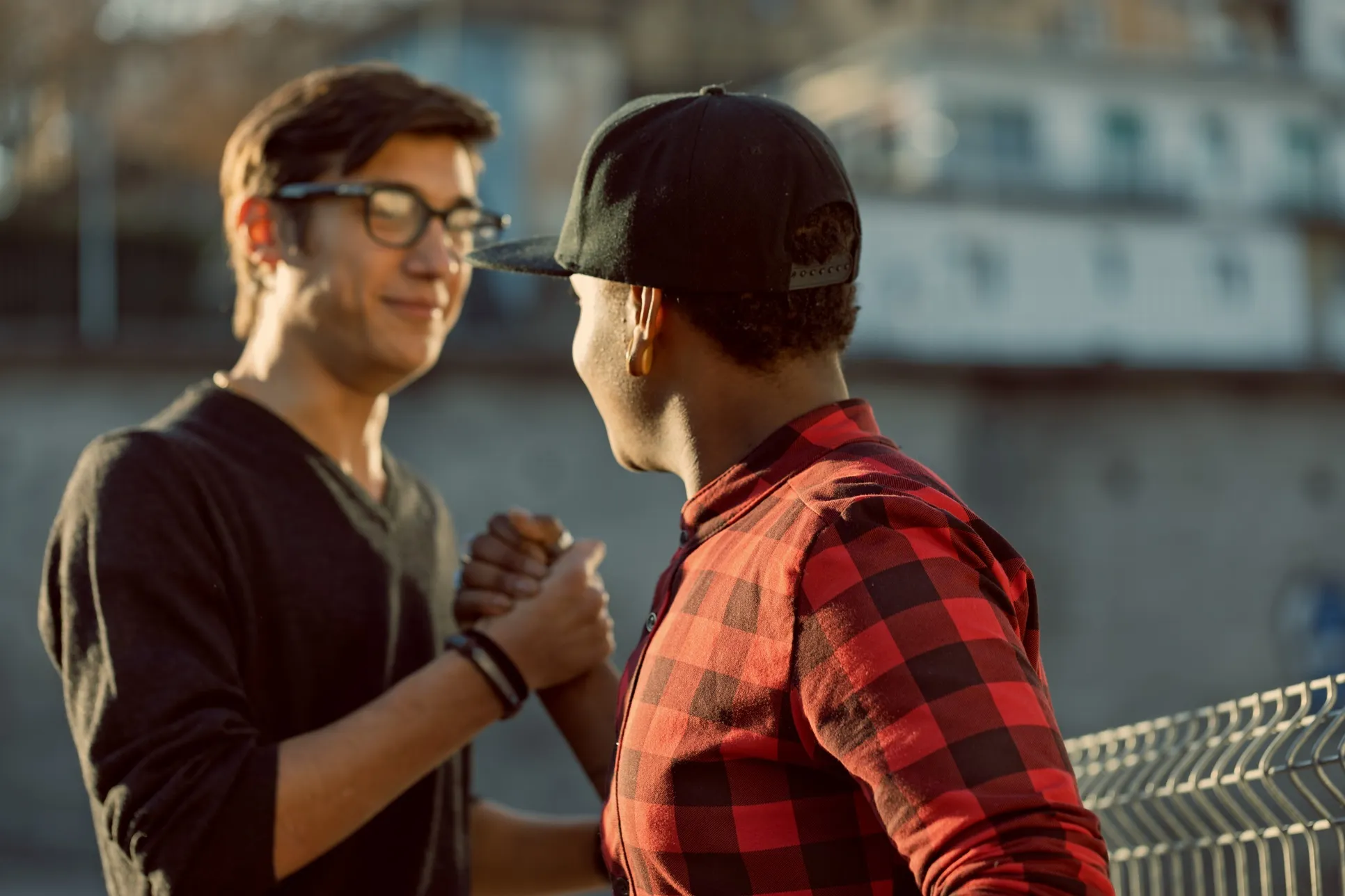 Two young men clasp hands in a friendly high-five.